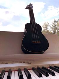 Close-up of guitar playing piano against sky