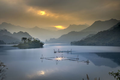 Scenic view of lake by mountains against sky during sunset