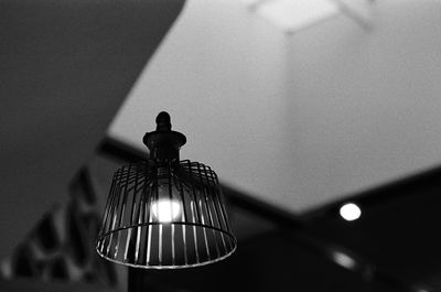 Low angle view of illuminated light bulb hanging on wall