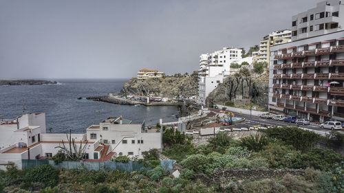 Buildings by sea against sky in city