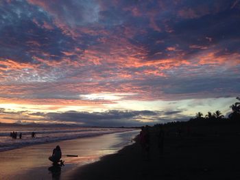 Silhouette woman walking on beach against sky during sunset