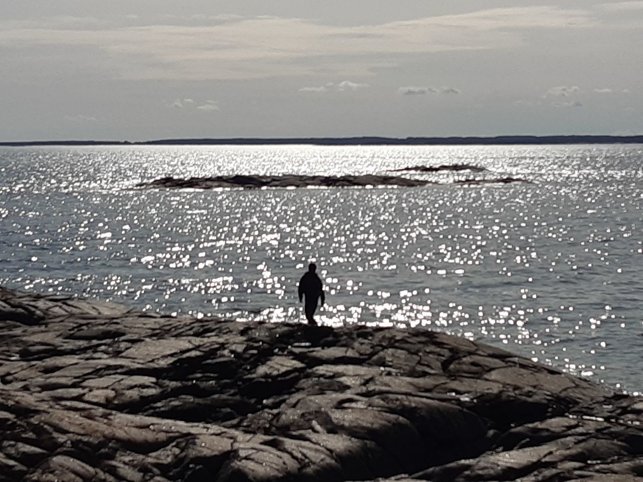 SILHOUETTE MAN STANDING ON ROCK AT BEACH AGAINST SKY