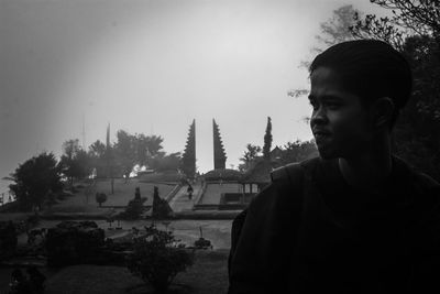 Portrait of teenage boy looking at temple against sky