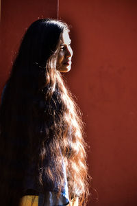 Woman looking away while standing against wall