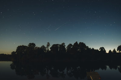 Reflection of trees in lake against sky at night