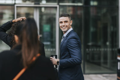 Side view of smiling male business professional looking away while holding insulated drink container