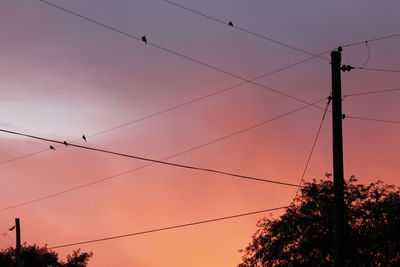 Low angle view of power lines against sky at sunset