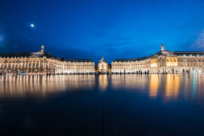 View of illuminated building against blue sky at night