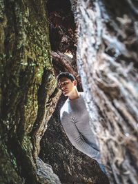 Portrait of smiling young woman against tree trunk