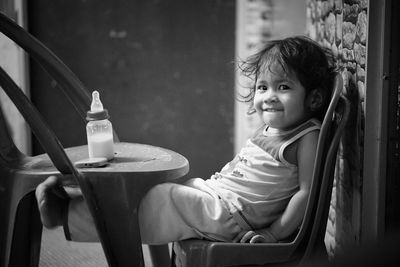 Portrait of cute girl sitting on chair at home