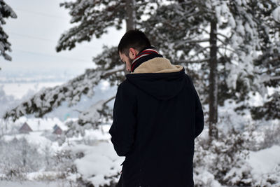 Rear view of person standing by tree during winter