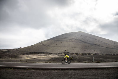 Man riding bicycle on mountain against sky