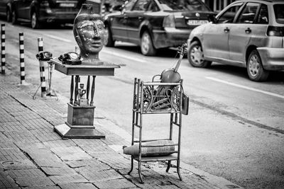 Items out in the street in front an antiquarian shop violin and telephone inca statue wooden table