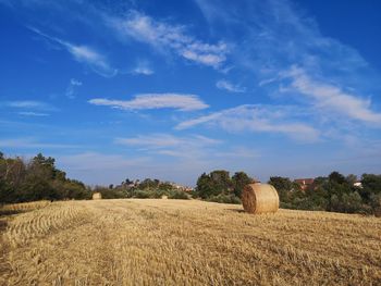 Hay bales on field against sky