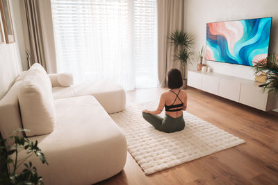 Rear view of woman sitting on sofa at home