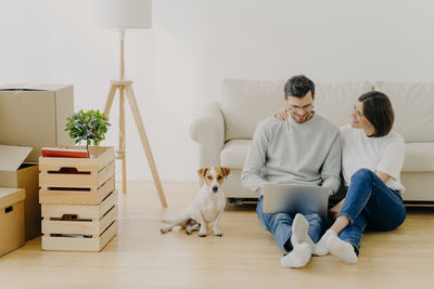 Full length of couple using laptop while sitting at new home