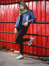 Portrait of young woman standing against railing