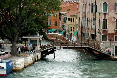 Canal amidst buildings and trees in city