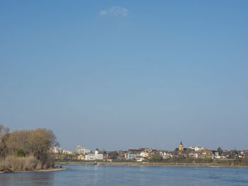 Sea by buildings against clear blue sky