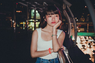 Portrait of young woman standing on car at night