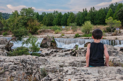 Rear view of boy looking at waterfall