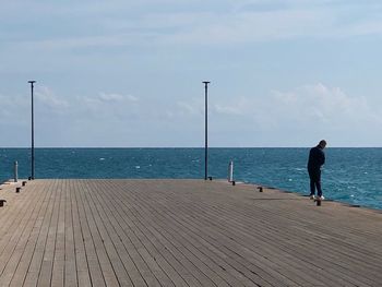 Rear view of man standing by sea against sky