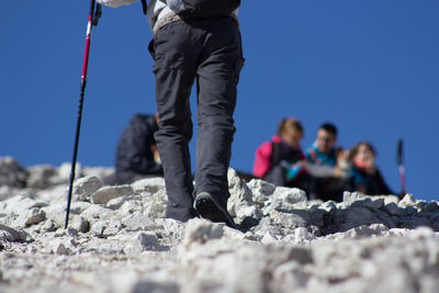 Low section of man hiking against clear sky