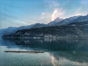 Scenic view of lake by mountains against sky