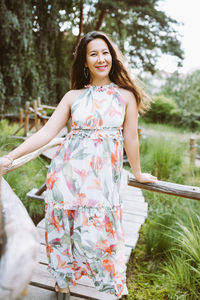 Happy mixed-race japanese woman in romantic floral maxi dress in park