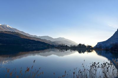 Scenic view of lake and mountains against blue sky