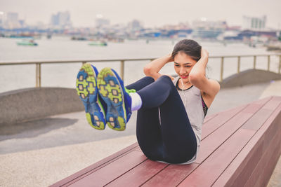Woman listening music while exercising against river