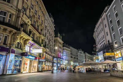 Illuminated street amidst buildings in city at night