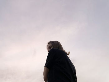 Low angle portrait of woman standing against sky