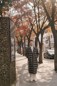 Portrait of man standing by footpath in city