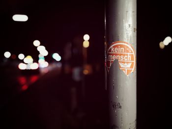 Close-up of illuminated text on pole at night