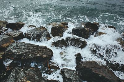 High angle view of sea splashing against rocks 