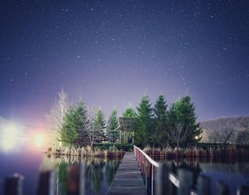 Pier over lake against sky at night