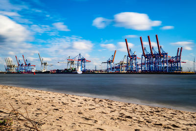 Cranes at commercial dock against sky