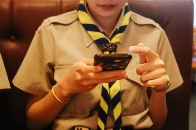Midsection of woman wearing uniform using mobile phone