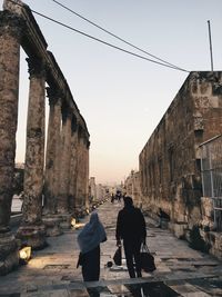 Rear view of people walking on street amidst buildings in city