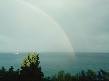 Scenic view of rainbow over sea against sky