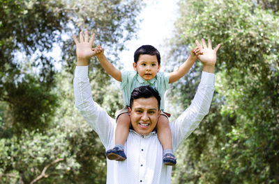 Portrait of happy father and son against trees