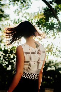 Rear view of woman standing against trees at park