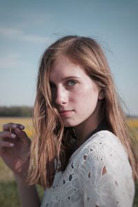 Close-up portrait of young woman against sky