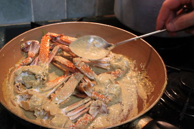 Cropped hand preparing food in cooking utensil at kitchen