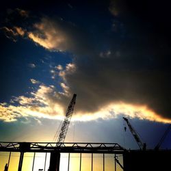 Low angle view of crane against cloudy sky