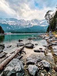 Scenic view of lake by snowcapped mountains against sky