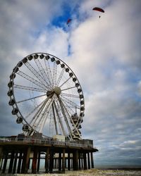 Low angle view of ferris wheel against cloudy sky