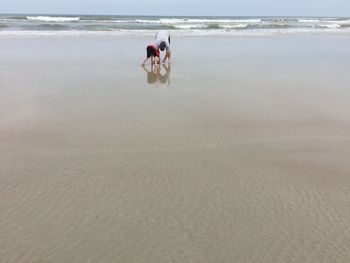 Father bending with son at sandy beach