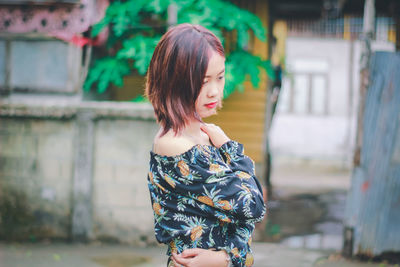 Beautiful young woman looking down while standing outdoors